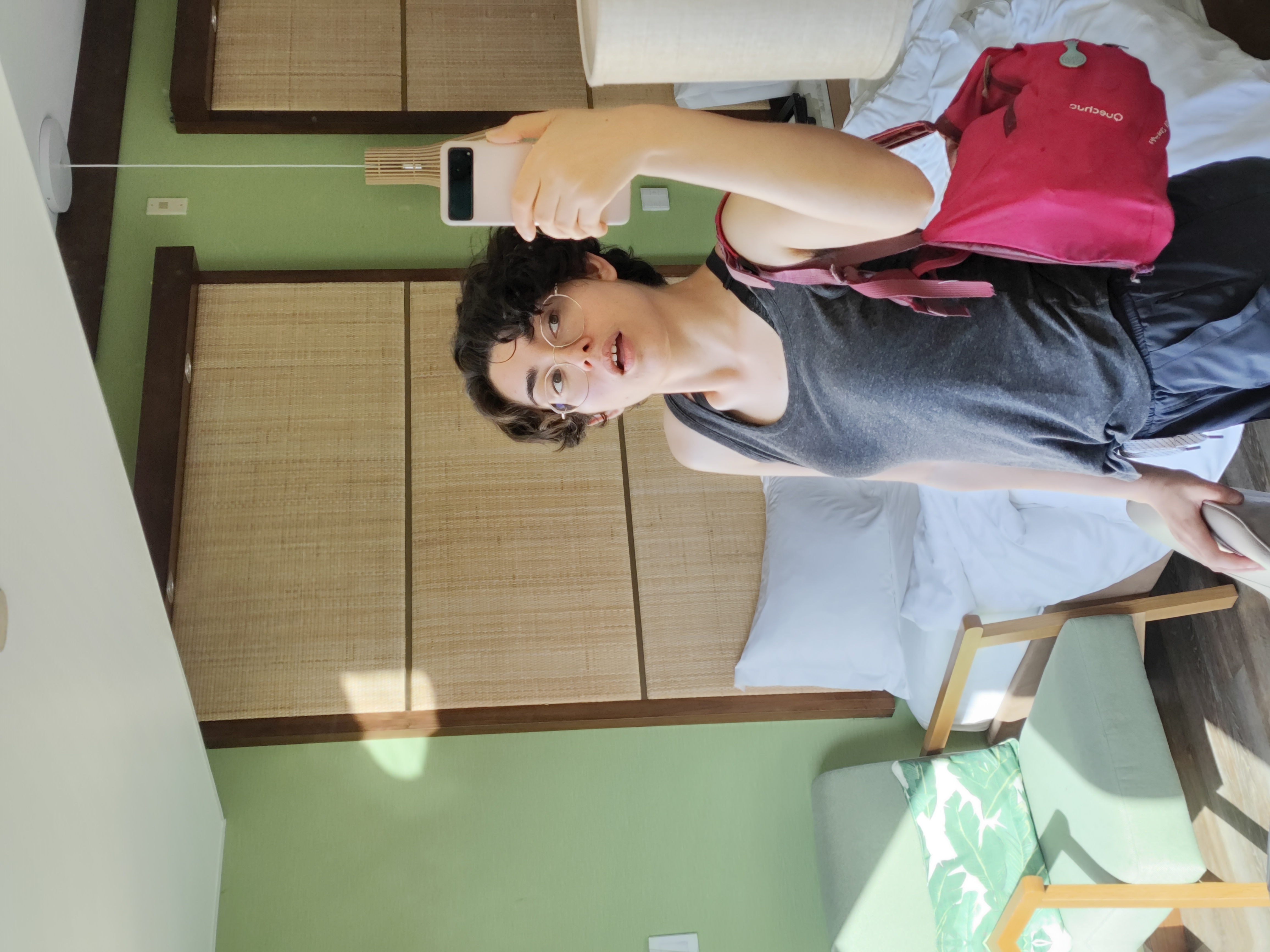 a mirror selfie of Kaiah. She holds her pink backpack over one shoulder, and looks slightly up at the camera with her mouth open
